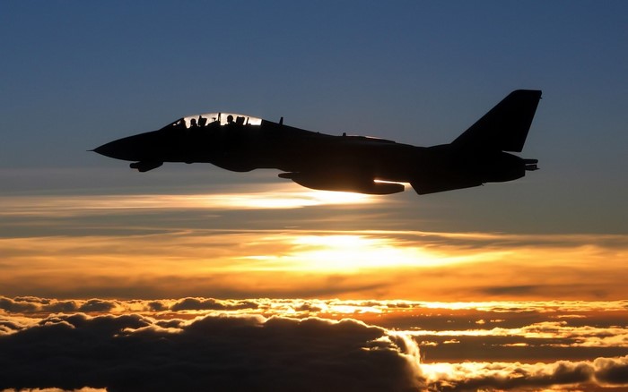 Grumman F-14 Tomcat silhouette at sunset over clouds