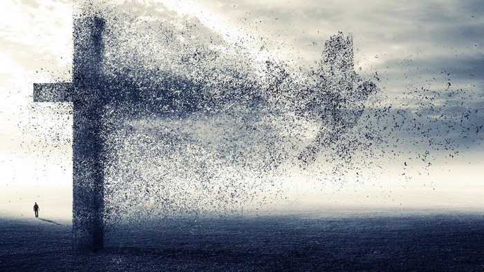 Cross disintegrating into particles with a man in the distance