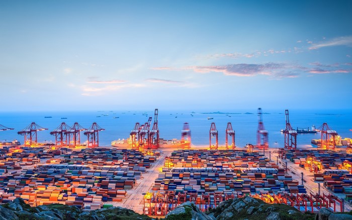 Container port with cranes and ships at dusk