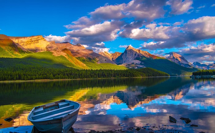 Boat on a lake with mountains and forest reflection