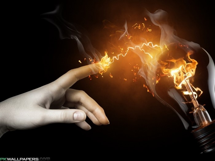 Hand touching a light bulb with electricity and fire