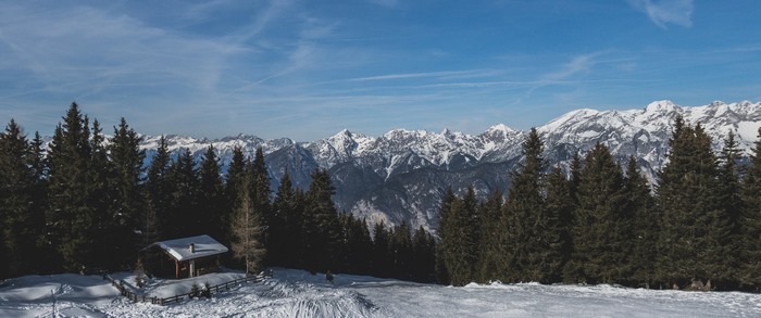 Snowy mountains and forest with a cabin