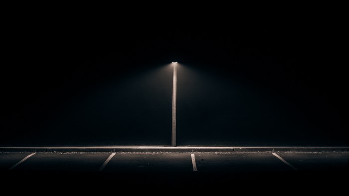 Street lamp illuminating a dark parking lot at night