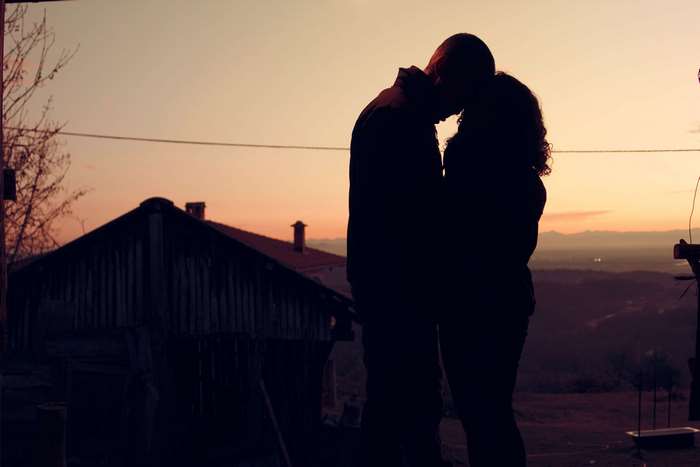 Couple kissing at sunset with a rustic cabin