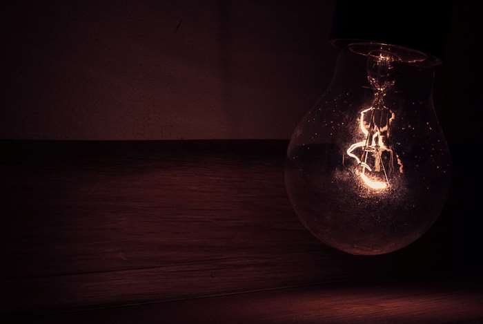 Close-up of a glowing light bulb on a wooden surface