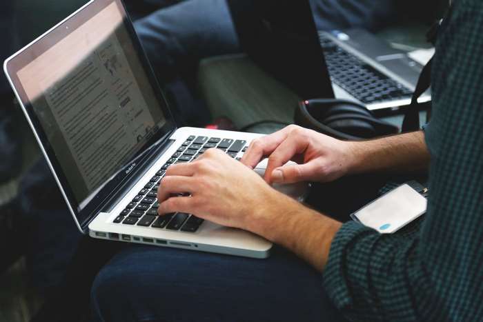 Person typing on a MacBook laptop screen
