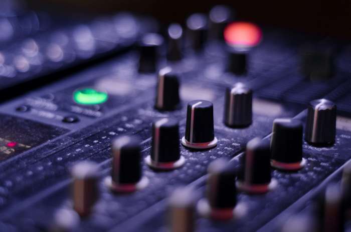 Close-up of a sound mixer with glowing lights and knobs