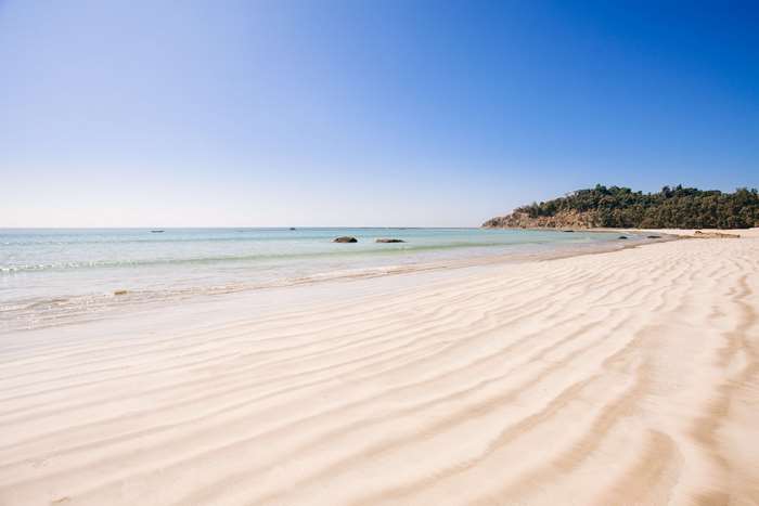 Sandy beach with calm ocean and blue sky