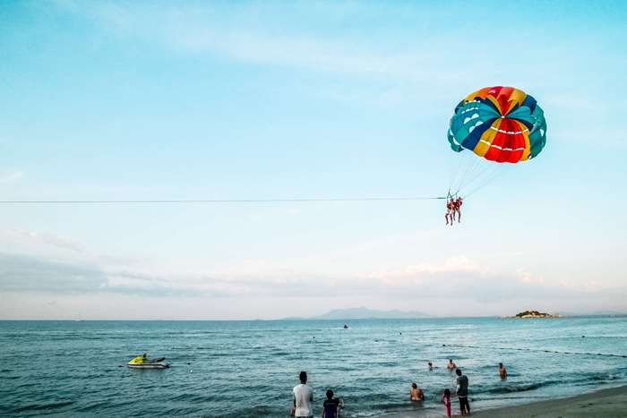 People parasailing over the ocean near a beach