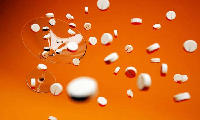 White pills spilling from cocktail glasses