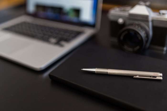 Laptop, camera, and pen on a desk