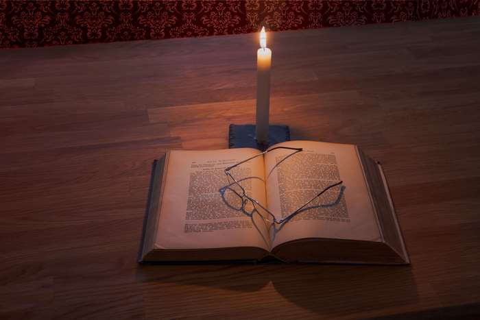 Open book and glasses lit by a candle