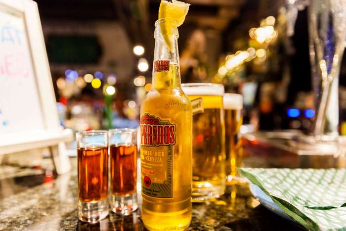 Bottle of beer with lemon and shots at a bar