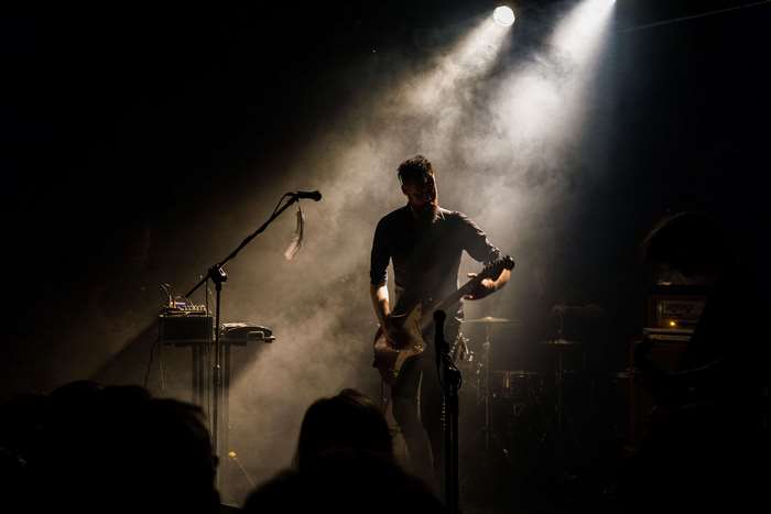 Musician playing guitar on stage with smoke