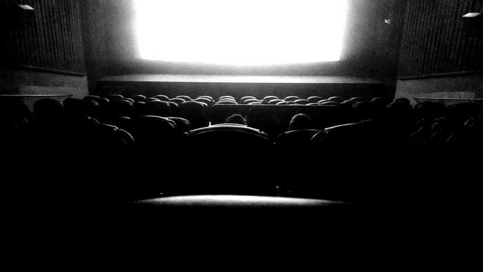Audience in a dark movie theater watching a bright screen