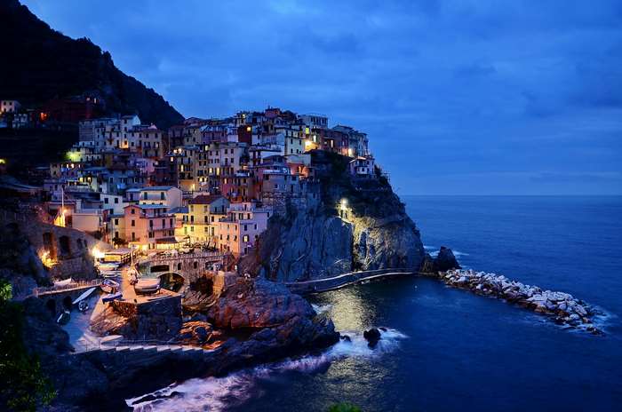 Cliffside village at night with ocean waves