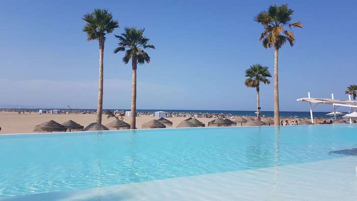 Infinity pool and beach with palm trees in Valencia, Spain