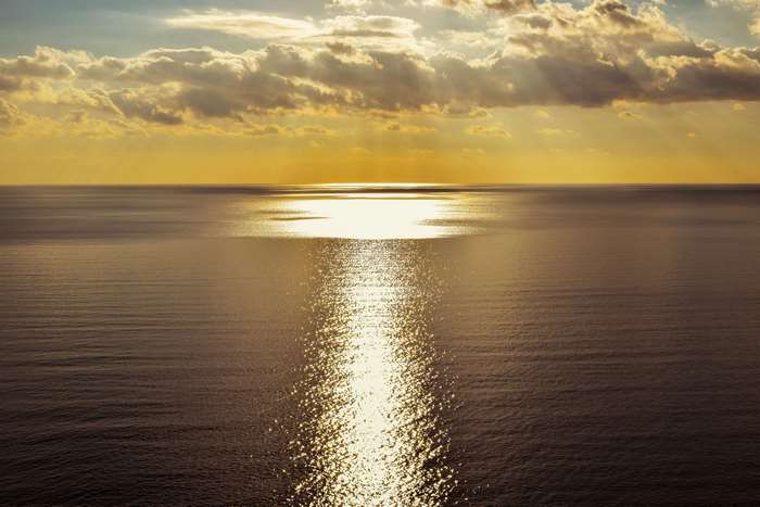Sunlight path on the sea under clouds