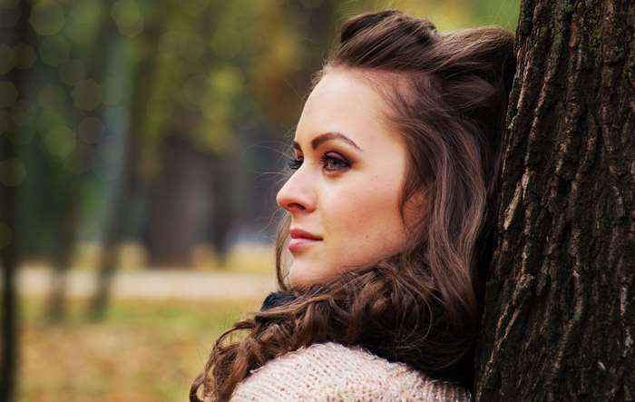 Woman leaning against a tree in autumn