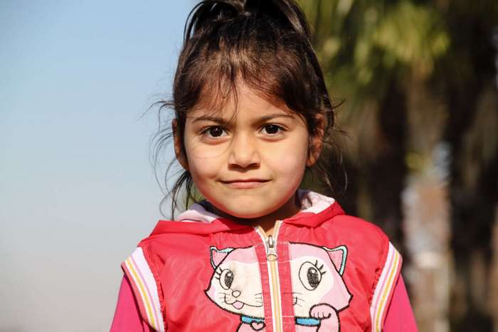 A young girl in a pink jacket with a cat design