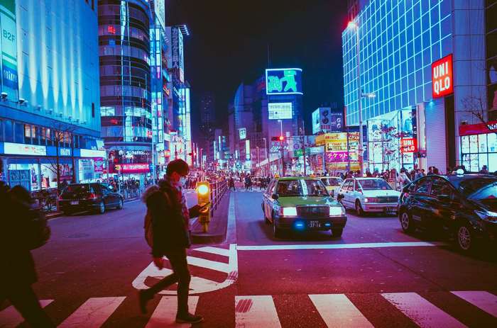 Man crossing street in neon-lit Tokyo at night
