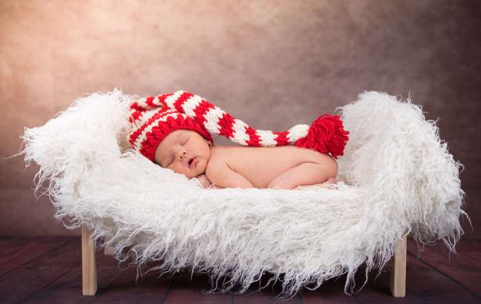 Baby sleeping in a fuzzy basket with a Santa hat
