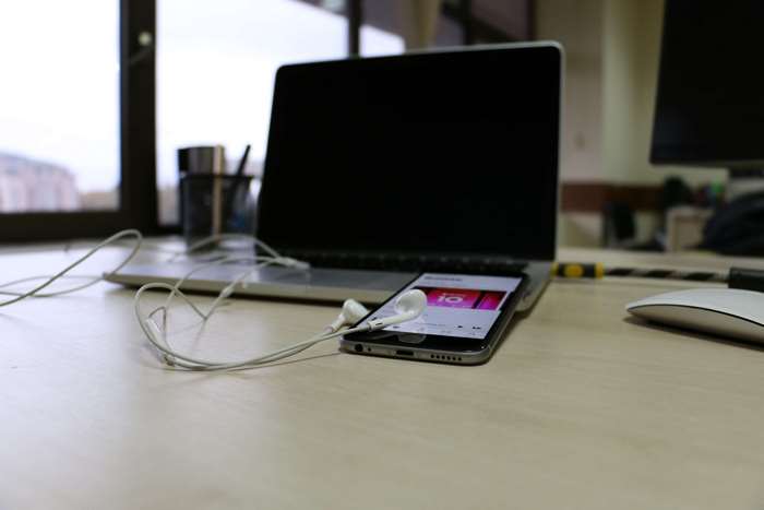 iPhone 6 with Apple Music on office table next to MacBook