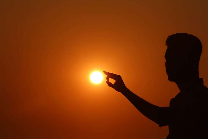 Silhouette of a man touching the sun at sunset 4K