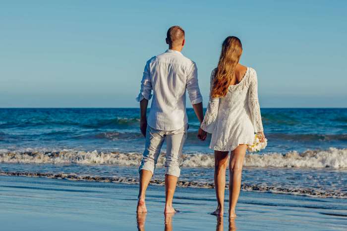 Couple holding hands on a beach at sunset