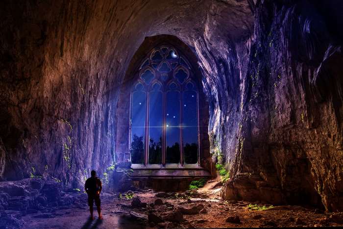 Man in cave looking at starry window