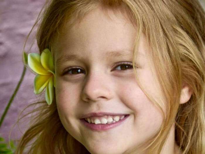 Smiling Young Girl with Yellow Flower