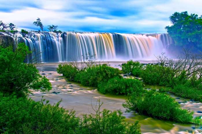 Long exposure waterfall with green bushes and blue sky