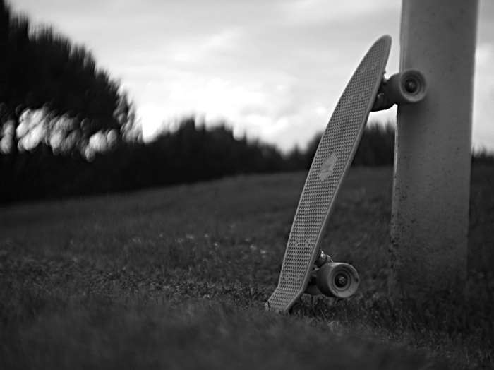 Penny skateboard leaning against a pole