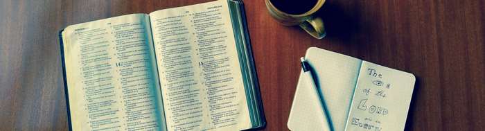 Open Bible, Coffee Cup, and Notebook on Wooden Table