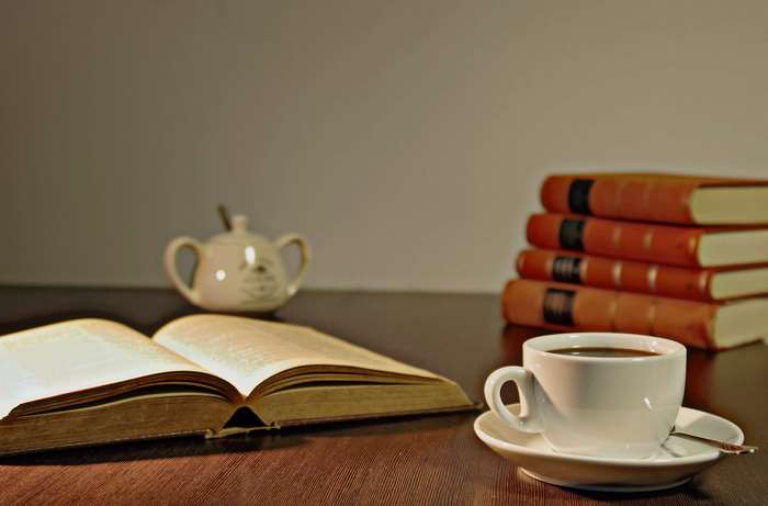 Open book and coffee cup with stack of books