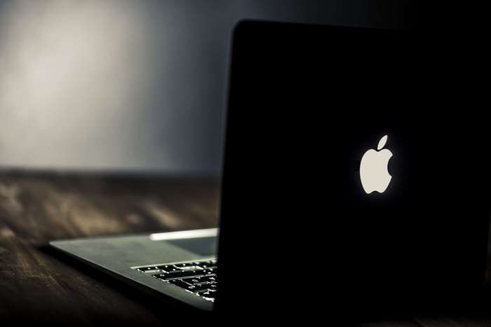 MacBook with glowing Apple logo on a wooden table