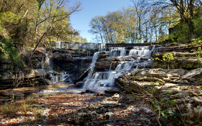 Cascading waterfall over rocky terrain with trees