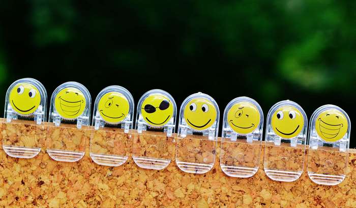 Eight smiley face clips on a cork board