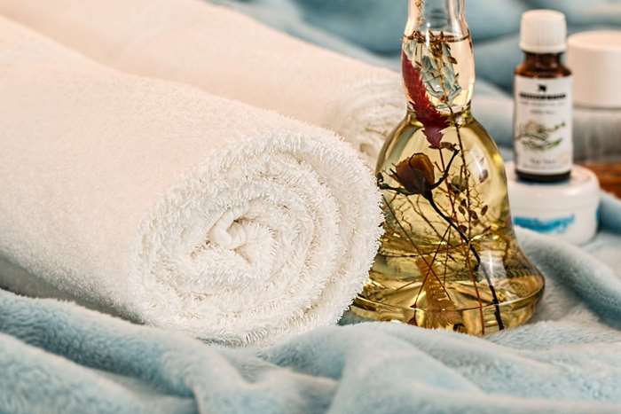 Spa essentials: rolled towels, aromatherapy oil, and lotions