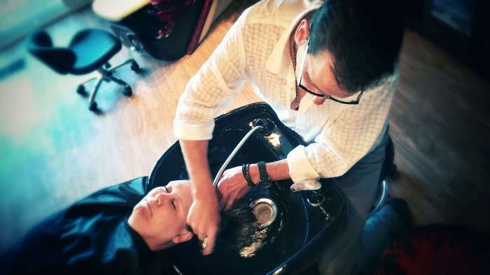 Hair stylist washing client's hair in salon