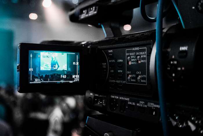 Close-up of a professional video camera recording a stage presentation