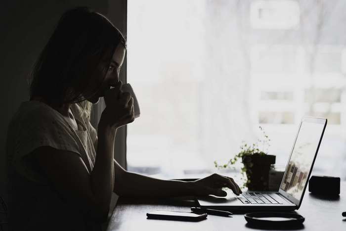Woman drinking coffee and working on a laptop