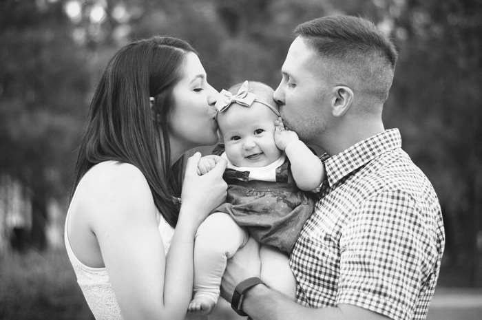 Parents kissing their baby girl