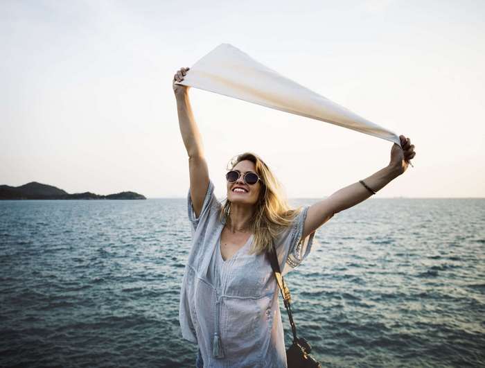 Woman holding scarf by the ocean