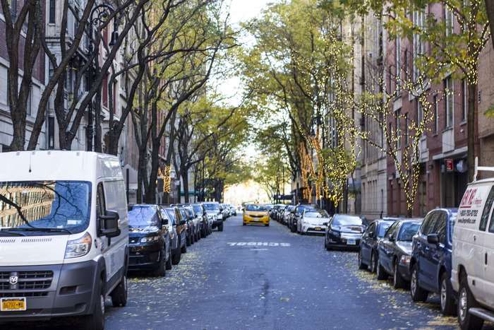 Yellow taxi and cars on a tree-lined street in New York City