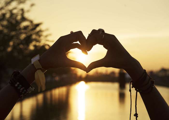 Hands forming a heart shape at sunset