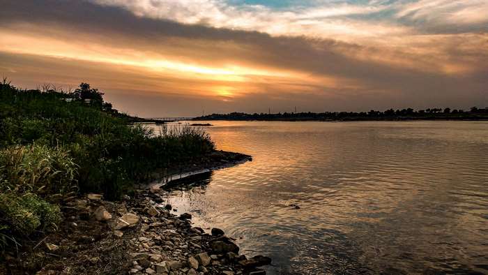 Sunset over a wide river with rocky shore