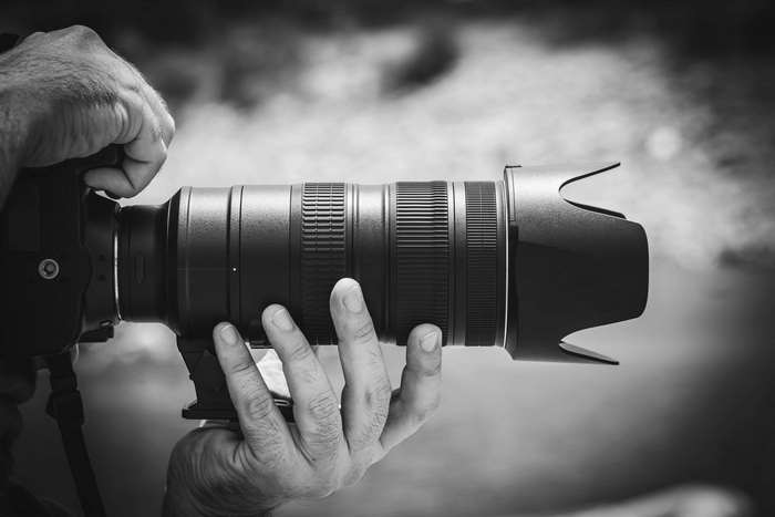 Black and white photo of a person holding a camera lens