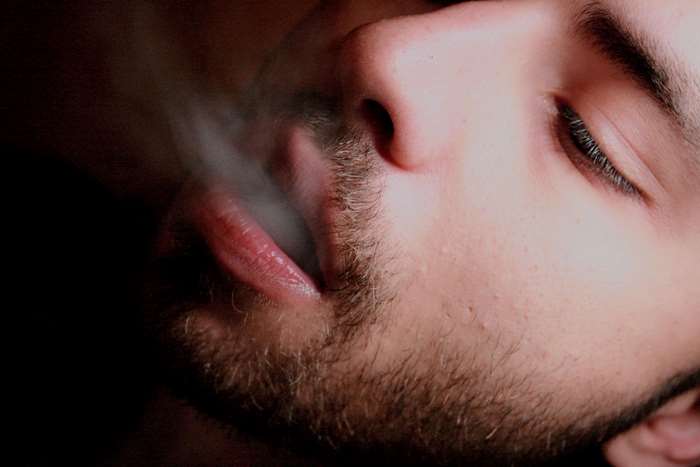 Close up of a man smoking, exhaling smoke