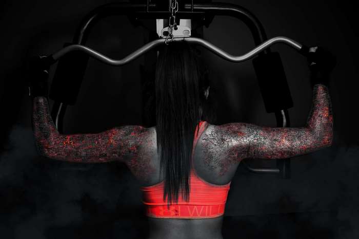 Woman with fiery arms exercising on a machine